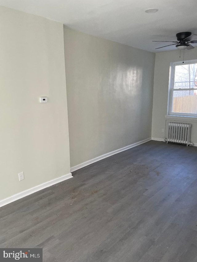 unfurnished room with radiator, dark wood-type flooring, and ceiling fan