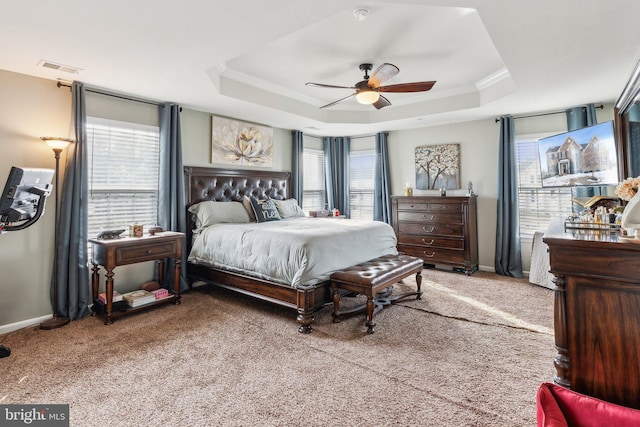 carpeted bedroom with a tray ceiling, ornamental molding, and ceiling fan