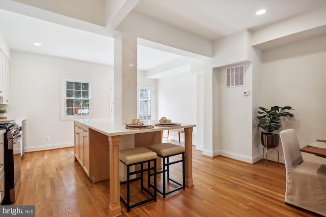 kitchen featuring gas range, a center island, light hardwood / wood-style floors, and a breakfast bar area