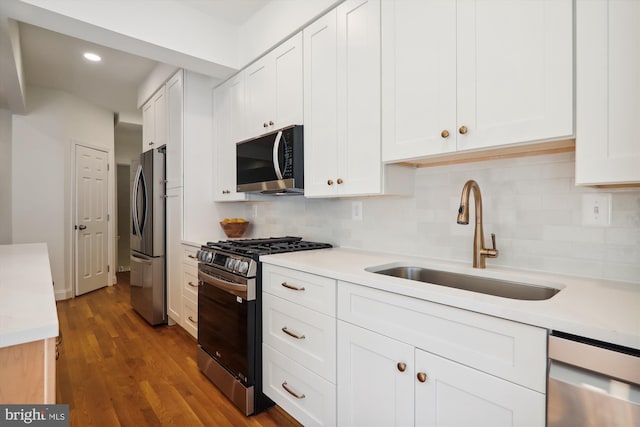 kitchen with sink, appliances with stainless steel finishes, white cabinetry, dark hardwood / wood-style floors, and tasteful backsplash