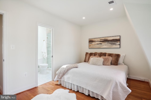 bedroom with ensuite bath and hardwood / wood-style floors