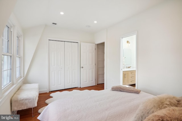 bedroom featuring ensuite bath, dark wood-type flooring, and a closet