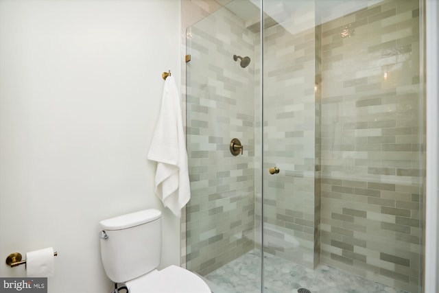 bathroom with a tile shower and toilet