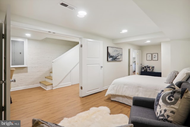 bedroom featuring electric panel and light wood-type flooring