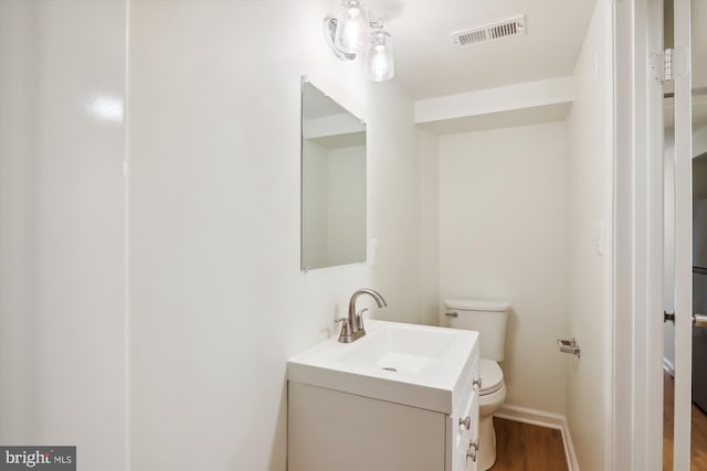 bathroom with hardwood / wood-style flooring, vanity, and toilet