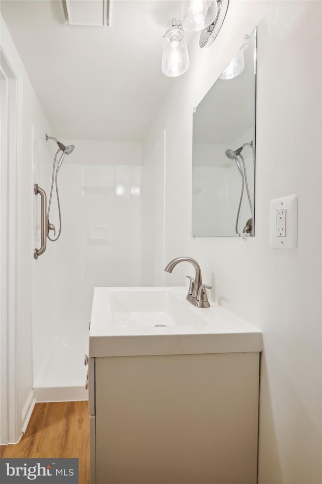 bathroom with walk in shower, vanity, and hardwood / wood-style floors