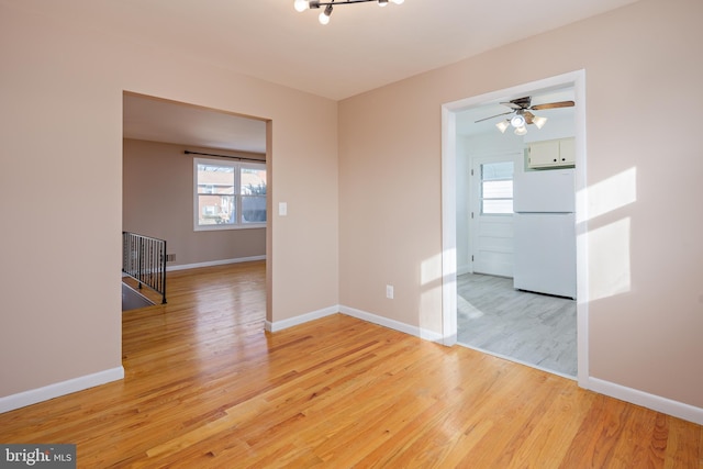 unfurnished room with a healthy amount of sunlight, baseboards, light wood-style floors, and ceiling fan