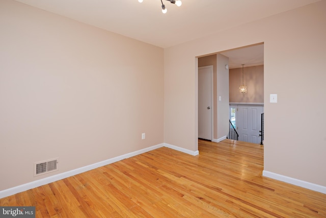 spare room featuring light wood-style flooring, baseboards, and visible vents