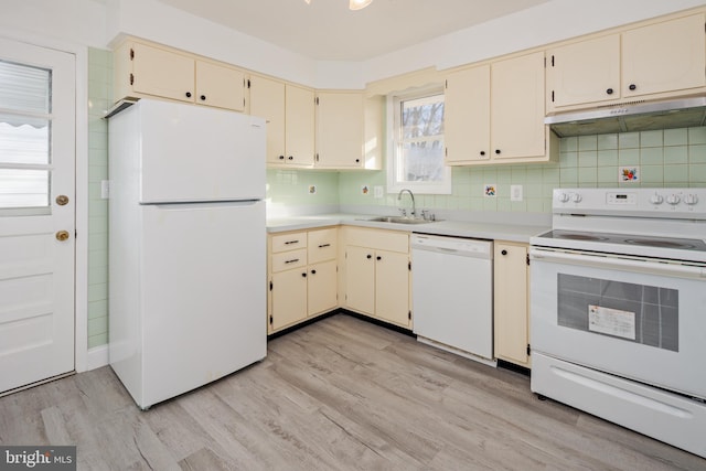 kitchen featuring white appliances, cream cabinets, and under cabinet range hood