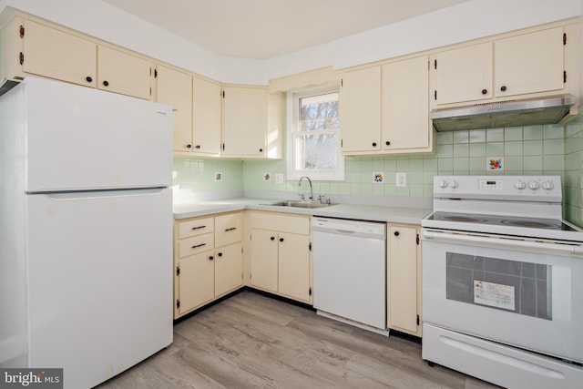 kitchen featuring light wood finished floors, under cabinet range hood, cream cabinets, white appliances, and a sink