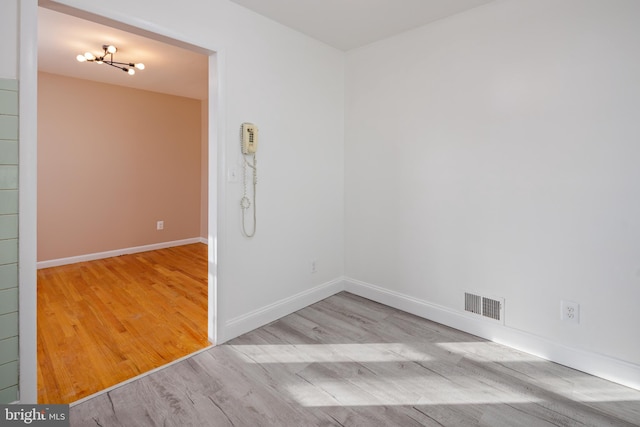 unfurnished room featuring wood finished floors, visible vents, and baseboards