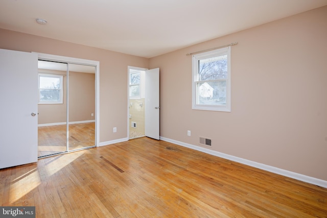 unfurnished bedroom featuring visible vents, multiple windows, light wood-type flooring, and baseboards