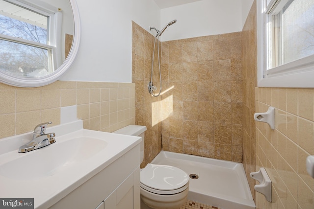 bathroom featuring toilet, tile walls, a stall shower, and vanity