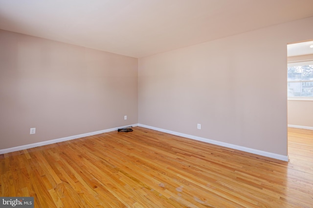 spare room with baseboards and light wood-style floors