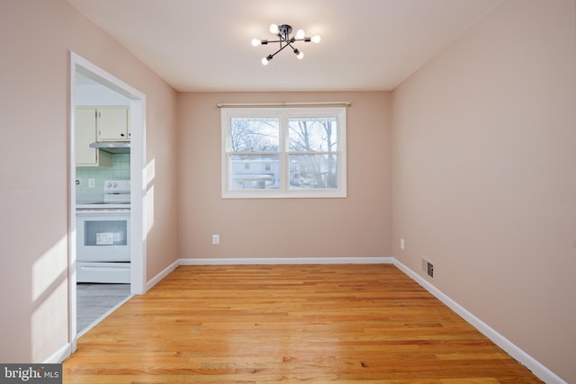 unfurnished dining area featuring a notable chandelier, visible vents, light wood-type flooring, and baseboards