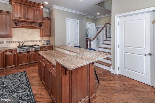 kitchen featuring a kitchen bar, a kitchen island, dark wood-type flooring, and stainless steel gas stovetop