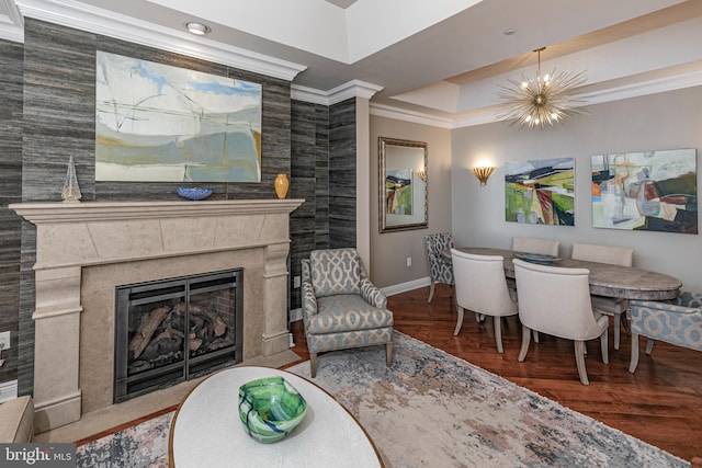 living room with a premium fireplace, ornamental molding, a chandelier, and wood finished floors