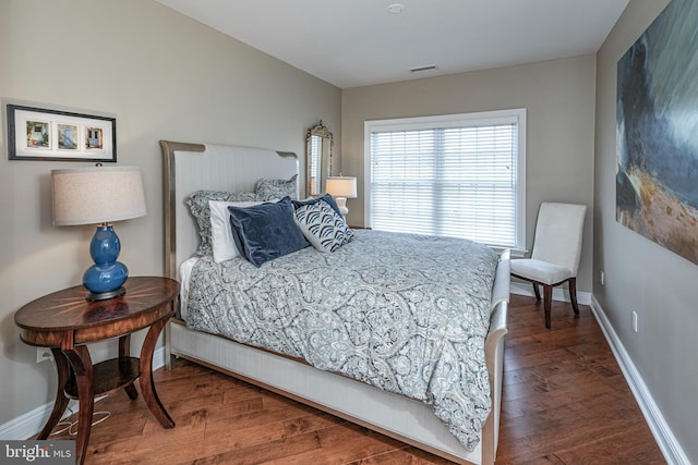 bedroom featuring visible vents, baseboards, and wood finished floors