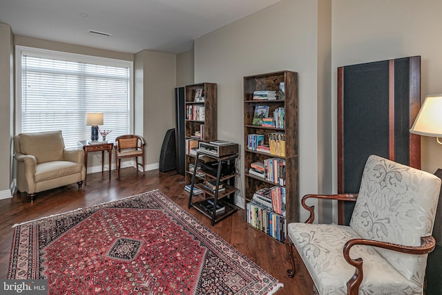 sitting room with dark wood-style flooring, visible vents, and baseboards