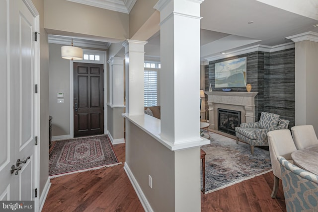 entrance foyer featuring ornate columns, dark wood-style floors, ornamental molding, and a premium fireplace