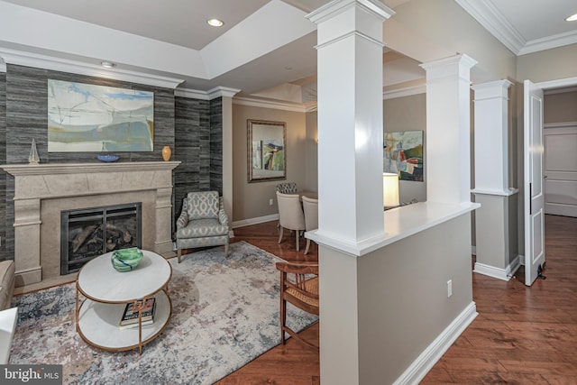 living room featuring baseboards, a premium fireplace, ornamental molding, dark wood-type flooring, and ornate columns