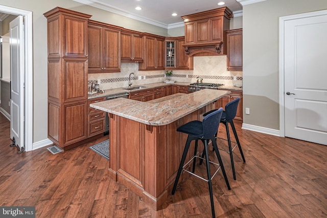 kitchen with a kitchen island, a sink, stainless steel dishwasher, brown cabinets, and light stone countertops