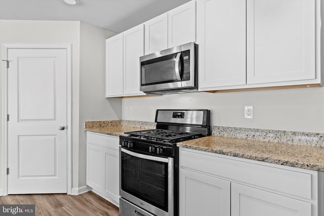 kitchen featuring light stone countertops, light hardwood / wood-style flooring, stainless steel appliances, and white cabinets