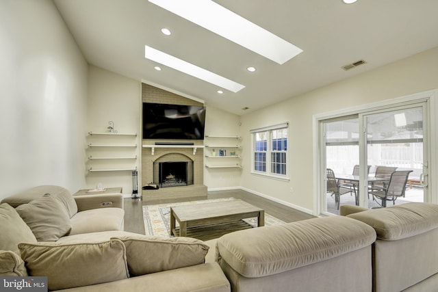 living room featuring hardwood / wood-style flooring, a fireplace, and lofted ceiling with skylight