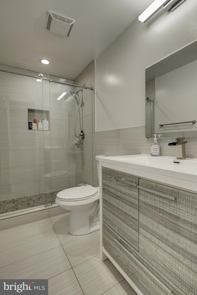 bathroom with walk in shower, toilet, tile patterned flooring, and tile walls