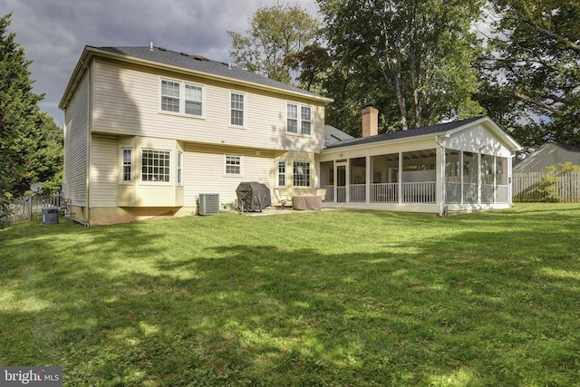 back of property featuring a sunroom, a yard, and central AC unit