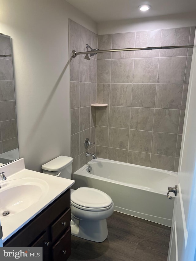 full bathroom with hardwood / wood-style flooring, vanity, toilet, and tiled shower / bath combo