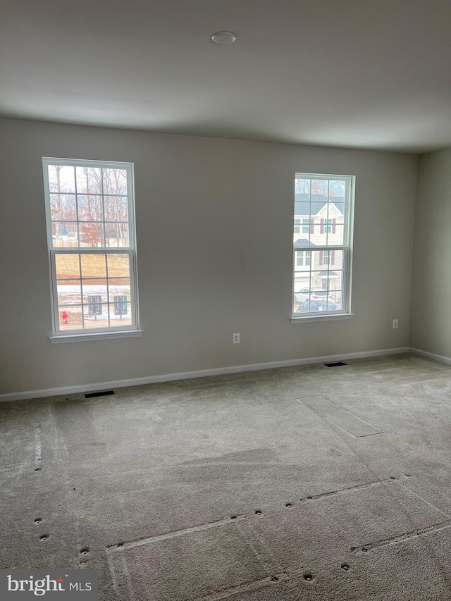 carpeted spare room featuring plenty of natural light