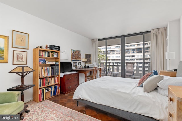 bedroom featuring dark parquet flooring and a wall of windows