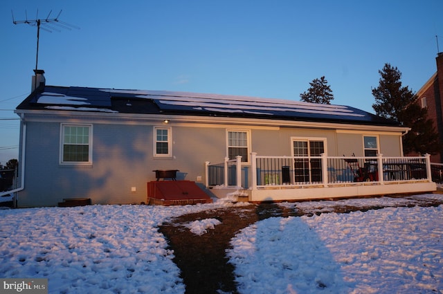 snow covered back of property featuring a deck