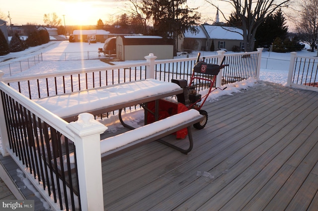 snow covered deck with a storage shed