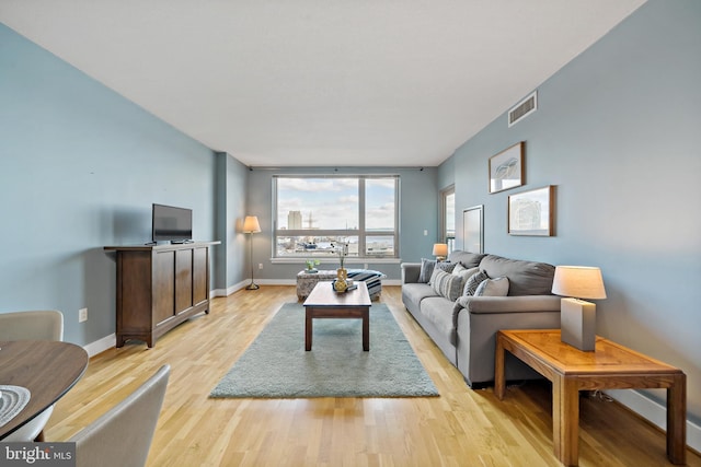 living area featuring light wood finished floors, baseboards, and visible vents