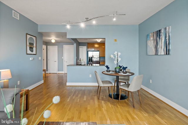 dining room with wood finished floors, visible vents, and baseboards