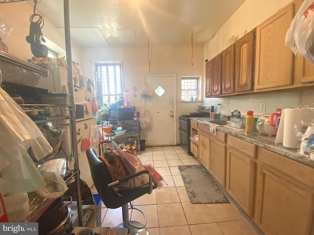 kitchen with appliances with stainless steel finishes, light stone countertops, sink, and light tile patterned floors