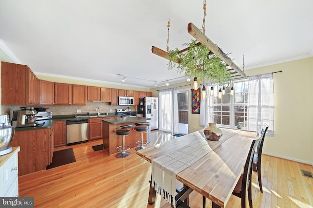 dining room featuring ornamental molding, rail lighting, sink, and light wood-type flooring