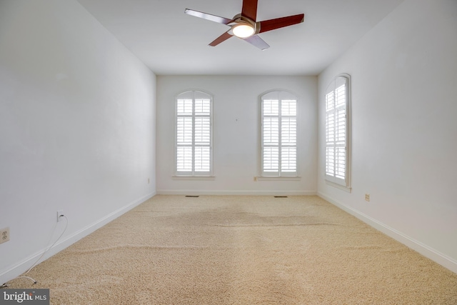 empty room featuring baseboards, ceiling fan, carpet flooring, and a wealth of natural light