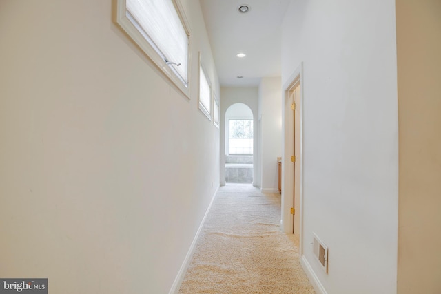 hallway featuring visible vents, arched walkways, baseboards, carpet flooring, and recessed lighting