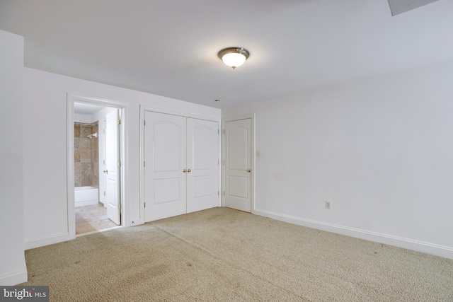 unfurnished bedroom featuring a closet, carpet, ensuite bathroom, and baseboards