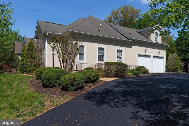 view of home's exterior featuring roof with shingles, stucco siding, and driveway