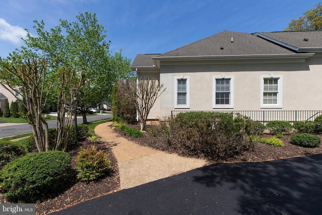 view of side of property with a shingled roof and stucco siding