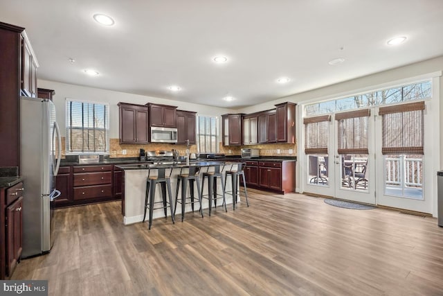 kitchen with backsplash, stainless steel appliances, dark wood-type flooring, and a breakfast bar area