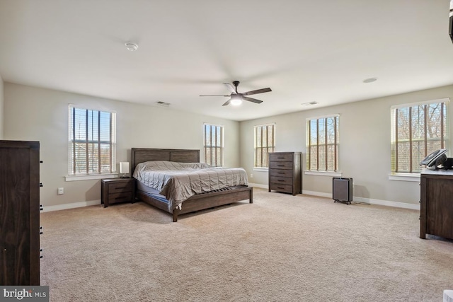 bedroom featuring visible vents, light colored carpet, baseboards, and ceiling fan