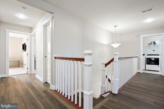hall with visible vents, an upstairs landing, washer / dryer, and dark wood-style flooring