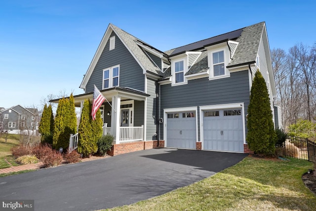 traditional home with fence, roof with shingles, covered porch, a garage, and driveway