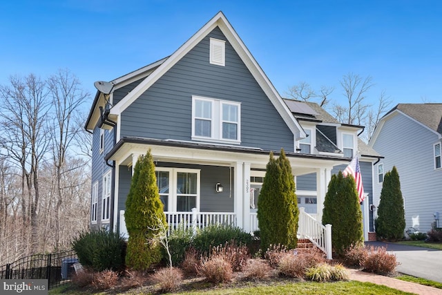 bungalow-style home with solar panels, aphalt driveway, and covered porch