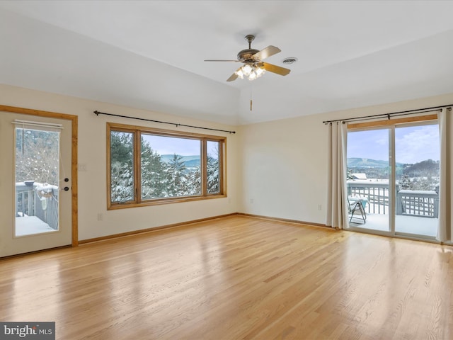 empty room featuring a ceiling fan, baseboards, vaulted ceiling, visible vents, and light wood-style floors